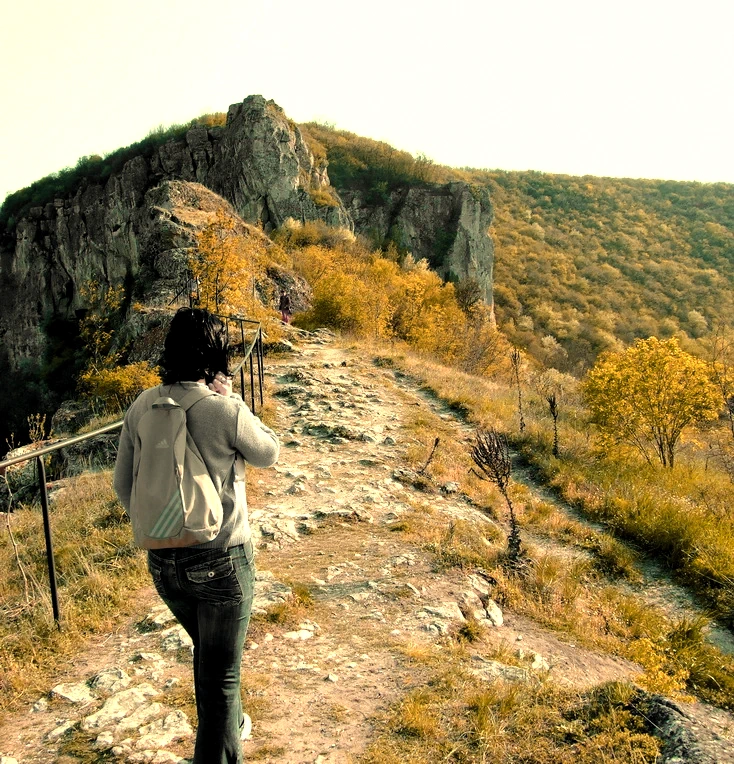 Cornelia Ilie, copywriter de turismo activo de Conie Hood, caminando por un sendero de montaña hacia una formación rocosa, representando el camino de la reinvención y la aventura